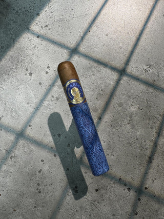 Cigar with blue wrapper and gold band on a concrete surface