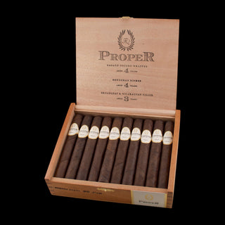 Open wooden box of cigars with 'Proper' branding on a white background