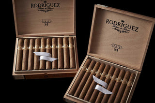 Two open wooden boxes of Rodriguez cigars on a black background