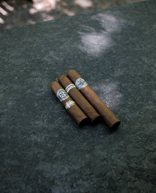 Four cigars with visible branding on a dark stone surface