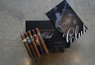 Creekside Cigar Club cigars and packaging on a concrete surface