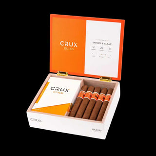 Open box of Crux Guild cigars with orange and white design on a black background