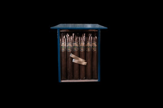 A blue wooden cigar display cabinet with dark brown cigars inside, shown against a solid black background.