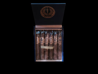 A box of cigars shown open against a black background. The dark blue-gray box has a circular gold-toned logo on the inside lid and a wooden band visible around the cigars inside.